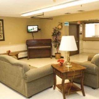 A cozy living room with sofas, a piano, and a television.