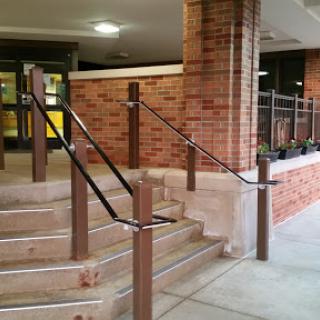 A set of stairs with a handrail leading to a building entrance.