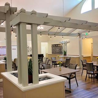 A cozy dining area with tables and chairs, complemented by indoor plants and warm lighting.