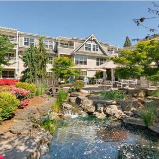 A beautiful residential building surrounded by lush gardens and a tranquil pond.