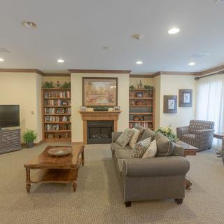 A cozy living room featuring a sofa, fireplace, bookshelves, and artwork.