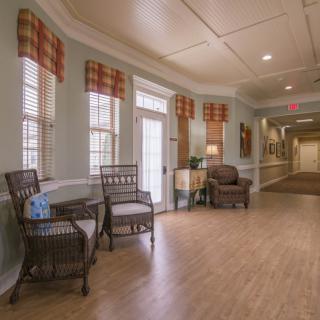 A cozy hallway with chairs and lamps along a wooden floor.