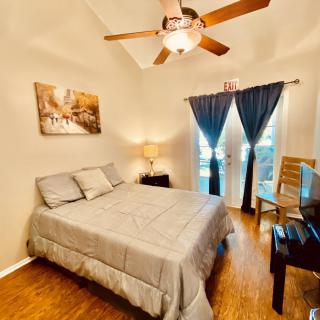 Cozy bedroom with a neatly made bed, ceiling fan, and soft lighting.