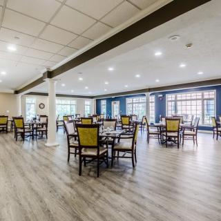 A spacious modern dining room with multiple tables and chairs, featuring large windows.