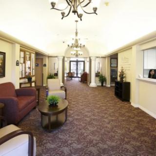 A well-lit lobby area featuring chandeliers, comfortable seating, and a reception desk.