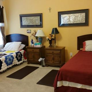 A cozy bedroom with two beds, nightstands, and decorative elements on the walls.