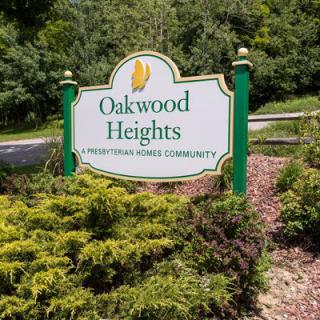 Entrance sign for Oakwood Heights, a manufactured home community surrounded by greenery.