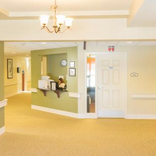 A well-lit hallway with a reception area, featuring a chandelier and doorways.