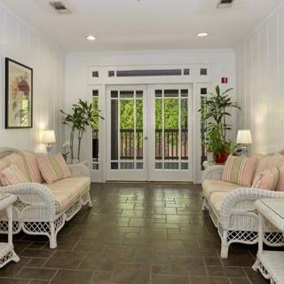 A cozy living room with white wicker furniture, plants, and ambient lighting.
