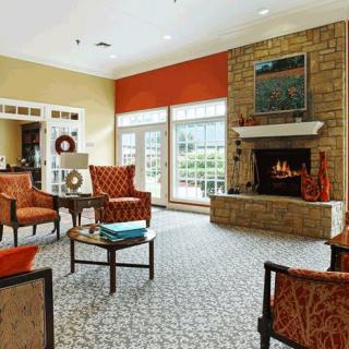 A cozy living room with a fireplace, armchairs, and large windows.