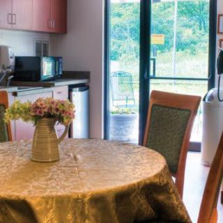 A cozy kitchen and dining area with a round table, floral centerpiece, and view to the outdoors.