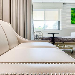A well-designed hospital lounge area featuring a comfortable sofa and a view of a patient room.