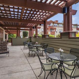 An inviting outdoor patio with tables and chairs under a pergola, perfect for dining in an urban setting.