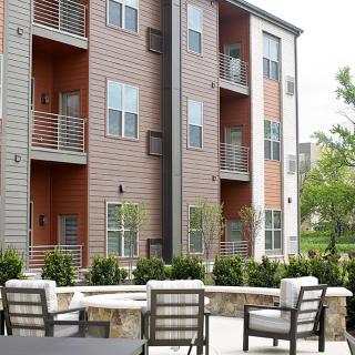 Modern apartment building with outdoor seating and landscaped surroundings.