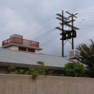 An urban scene featuring a building with power lines overhead against a cloudy sky.