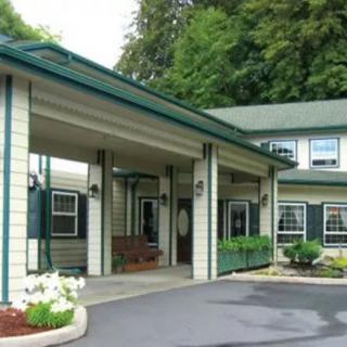 A building entrance with a covered driveway and surrounding greenery.
