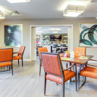 A modern dining area with orange chairs and contemporary artwork on the walls.