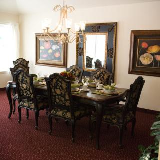 A well-decorated dining room featuring an ornate table set with six chairs, a chandelier, and framed artwork on the walls.