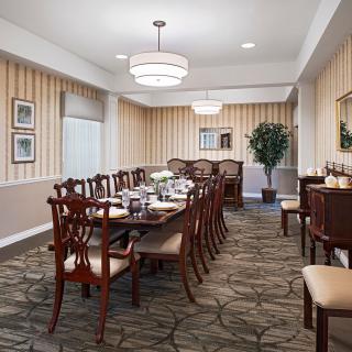 A formal dining room with an elegant table and chairs, featuring a chandelier and tasteful decor.
