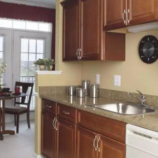 A modern kitchen with wooden cabinets, granite countertops, a sink, and adjacent dining area.