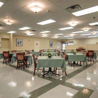 A well-lit dining room with neatly arranged tables and chairs, featuring decorative elements and polished flooring.
