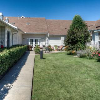 A well-maintained backyard with a lush lawn and garden landscaping under a clear blue sky.