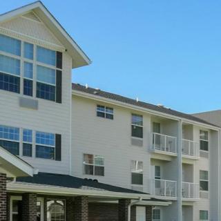 A modern apartment building with balconies and large windows under a clear blue sky.