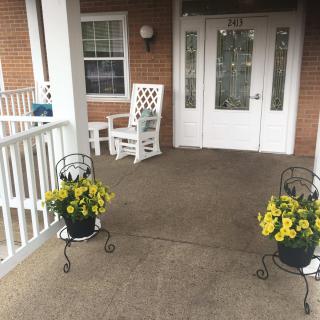 A welcoming front porch with rocking chairs and potted yellow flowers.