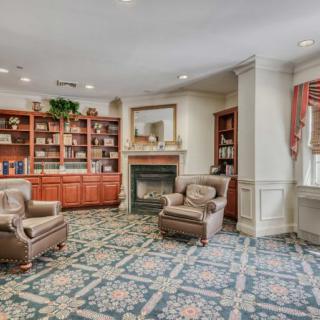 A cozy library with bookshelves, armchairs, and a fireplace.