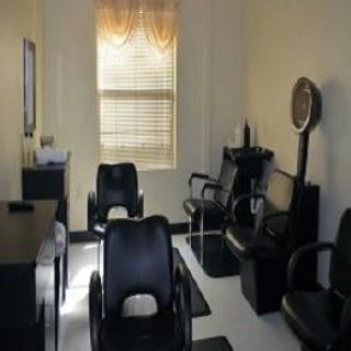 A well-lit salon interior featuring multiple chairs and a hair dryer station.
