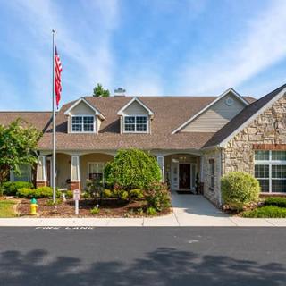 A stone and brick building with a flagpole in the front yard, set against a blue sky.