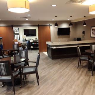 A modern lounge area featuring tables, chairs, and a reception desk.
