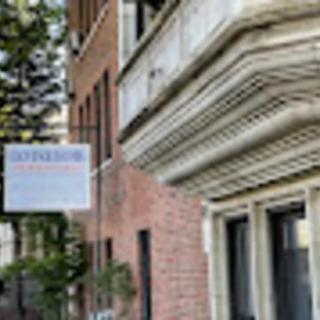 A street view of a building with a hanging sign in an urban area.