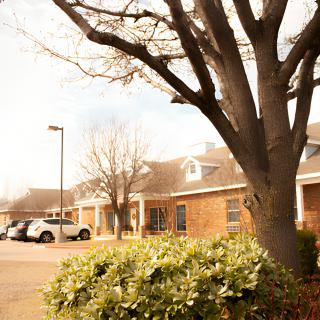A suburban building with a parking lot and surrounding trees.