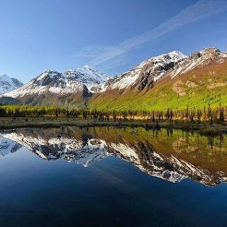 A breathtaking view of majestic mountains reflected in a tranquil lake under a clear blue sky.