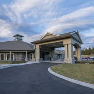 A building with a grand entrance and a driveway under a partly cloudy sky.