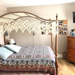 A cozy bedroom featuring a decorative canopy bed, colorful bedding, and wooden furniture.