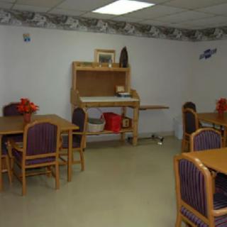 A simple room with several tables and chairs, featuring a wooden hutch against the wall.