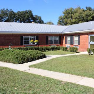 A well-maintained brick building with landscaped lawns and a clear pathway.