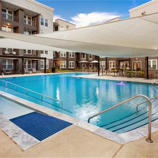 Outdoor swimming pool at an apartment complex with a shade canopy.