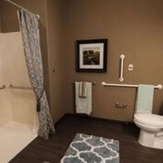 A well-designed bathroom with accessibility features, including a shower, toilet, and towel racks.