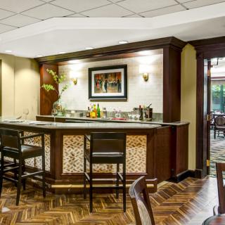 A cozy bar area with a wooden counter and chairs, stylish lighting, and decorative elements.
