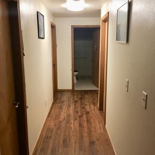 A hallway with wooden floors leading to a bathroom.