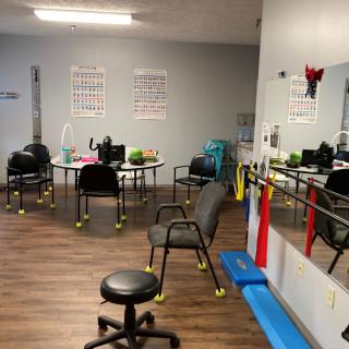 A physical therapy room equipped with chairs, exercise equipment, and mirrors.
