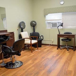 An interior view of a hair salon featuring chairs, mirrors, and hair dryers.
