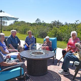 A group of people sitting outside enjoying a sunny day and engaging in conversation.