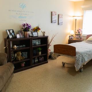 A cozy bedroom setup featuring a hospital bed, decorative shelf, and comfortable seating.