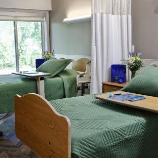 A clean and well-lit hospital room with two beds, equipped for patient care.