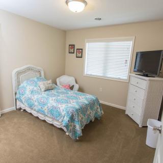 A cozy bedroom with a single bed, a dresser, and a TV.