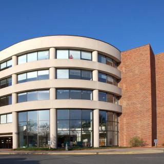 A modern office building with a curved facade and large windows under a clear blue sky.